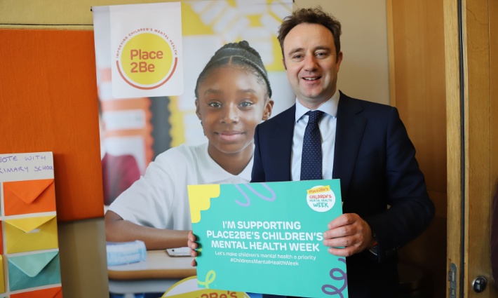 Danny Chambers holding a sign saying 'I'm supporting Place2Be's Children's Mental Health Week' and smiling