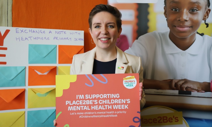 Carla Denyer is holding a sign saying 'I'm supporting Place2Be's Children's Mental Health Week' and smiling