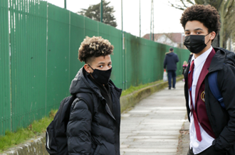 Two school boys wearing face masks outside the school gates