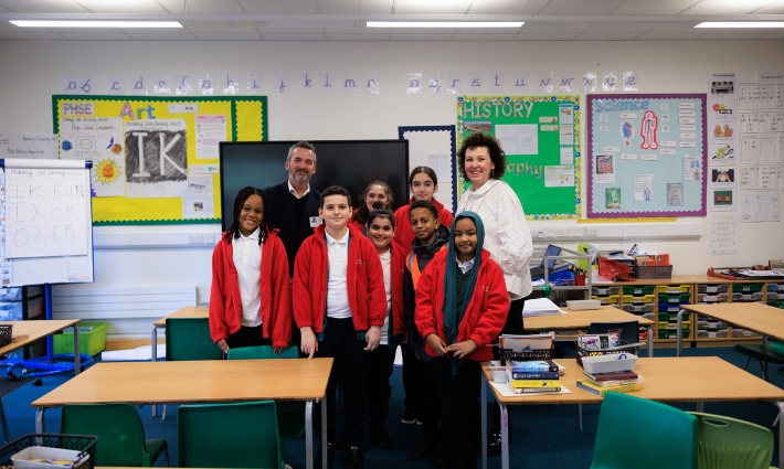 Catherine Roche, Chief Executive of Place2Be, and Gordon Banks, Global Director of The Daily Mile, standing at the front of the classroom with pupils from Churchfield primary school