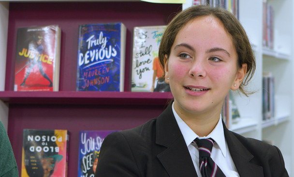 Secondary-aged pupil talking to others in a school library
