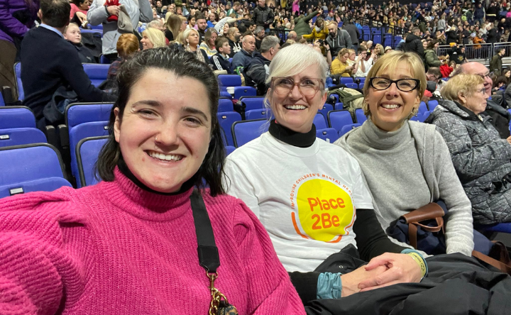Three Place2Be staff and volunteers taking a selfie sitting in the audience of a Young Voices concert