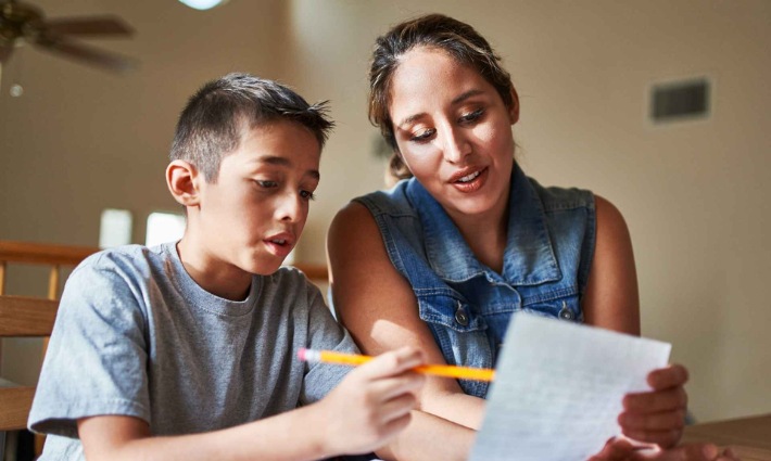 A parent sitting with their child at home. They are writing together.