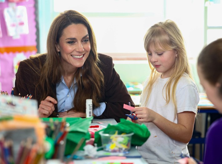 The Princess sitting at the table with a pupil who is doing an arty activity