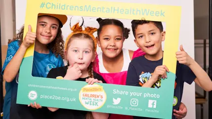 Four children smiling holding selfie frame