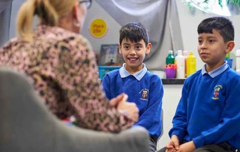 Adult staff member talking to two primary school pupils