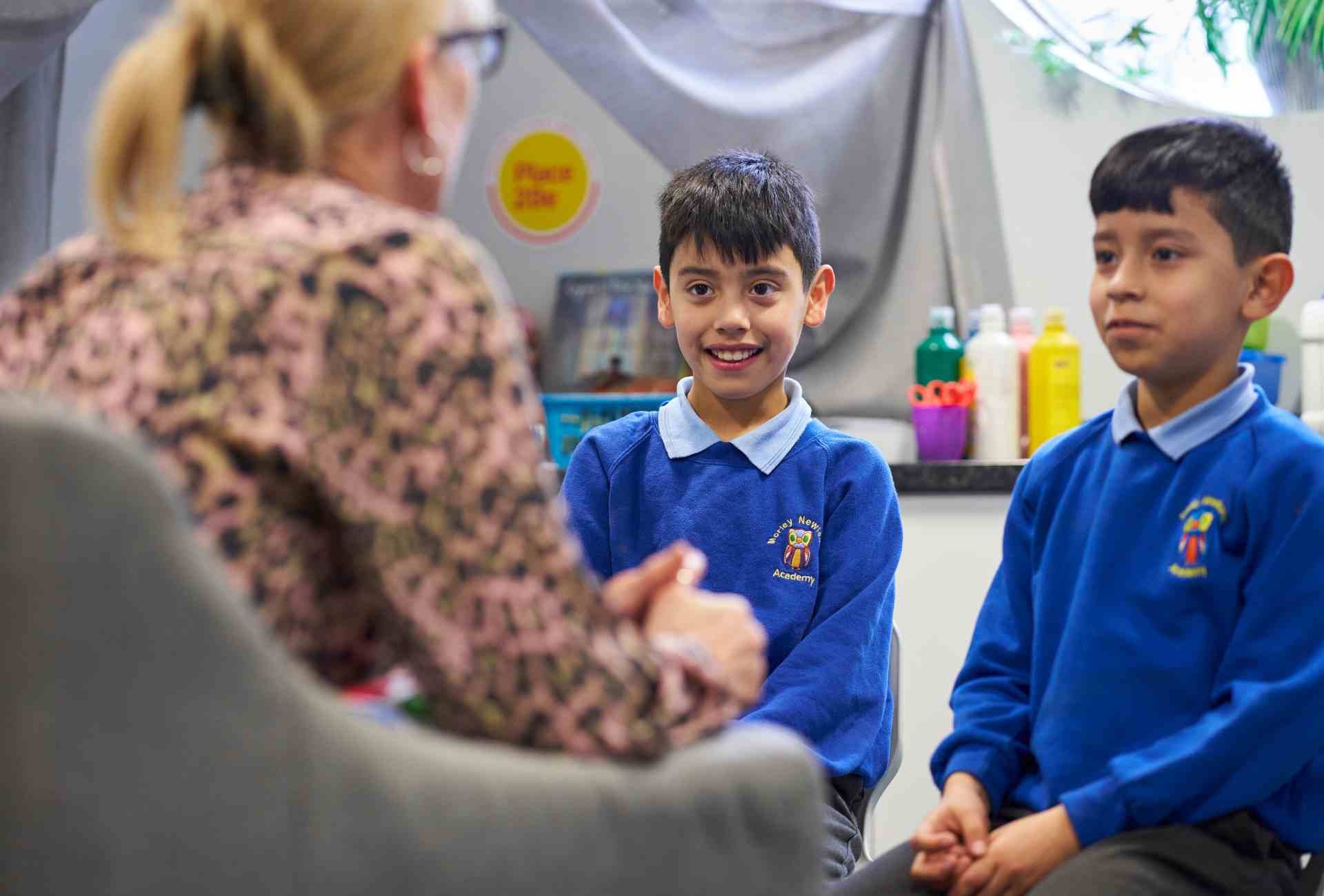 Place2Be counsellor talking to two primary school pupils in classroom therapy setting