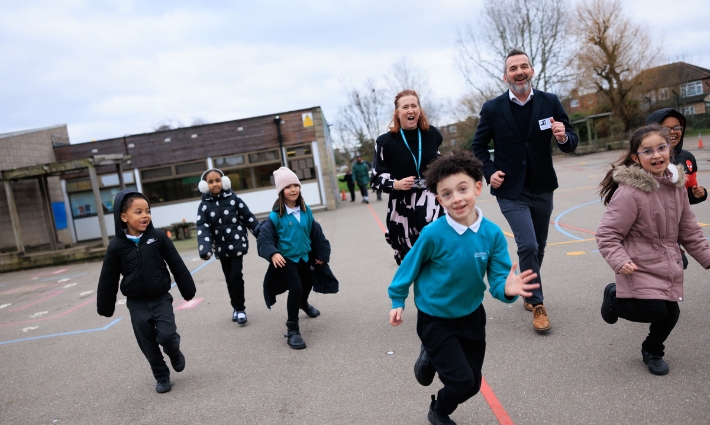 Gordon Banks running with 6 pupils and one staff member from Churchfield Primary in the playground