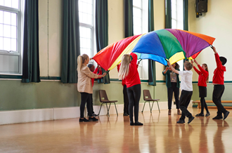 group of children playing with a colourful parachute