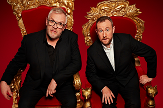 Greg Davies and Alex Horne, the presenters of Taskmaster, sat on golden thrones and looking up towards the camera. 